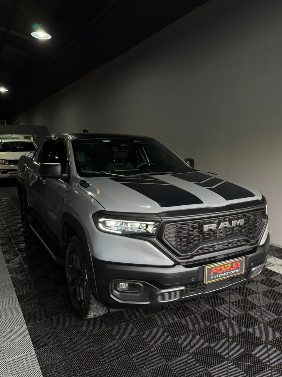 RAM Rampage Rebel gris con capot negro, tres cuartos de frente, en el showroom