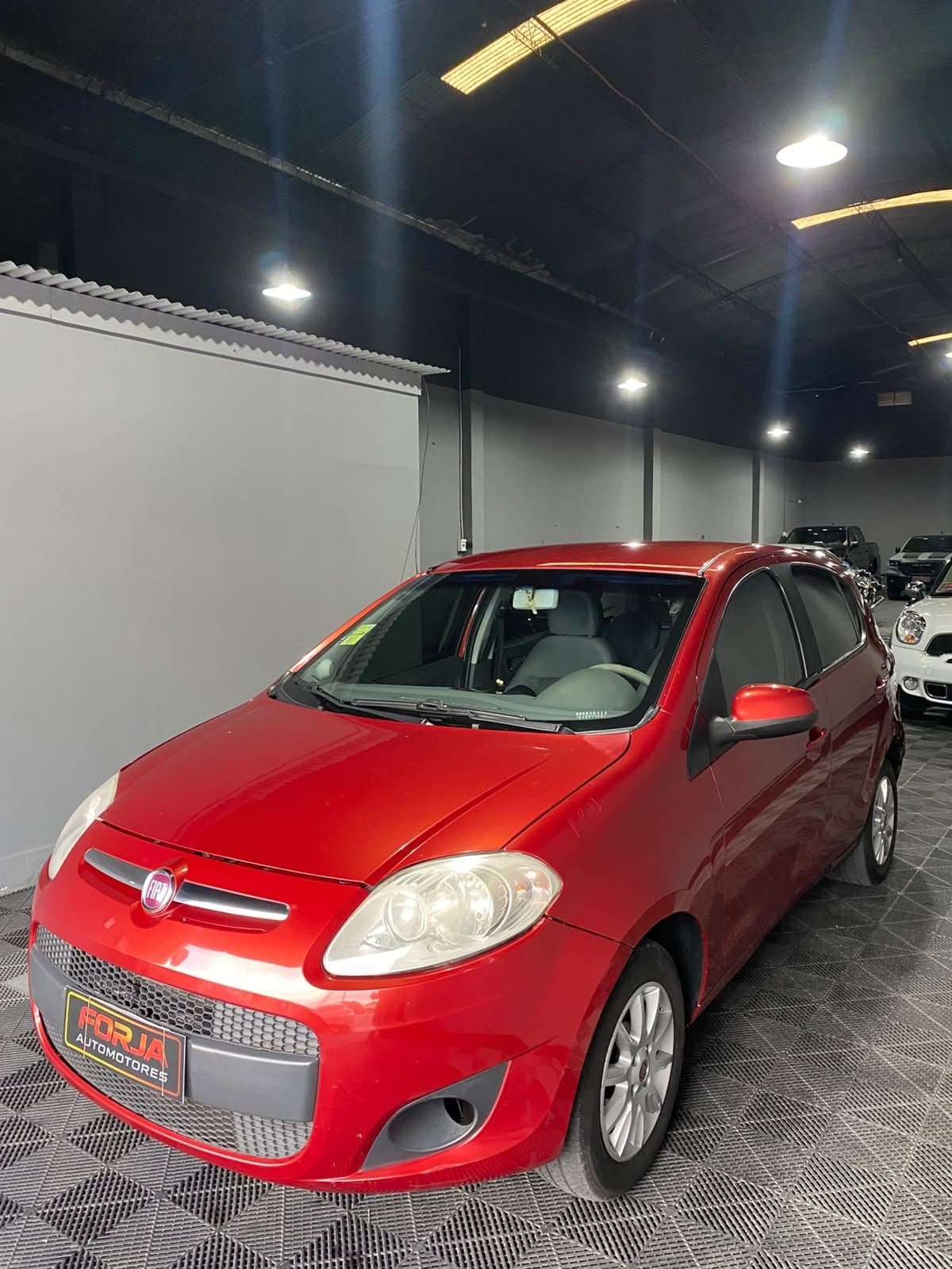 Fiat Palio rojo, frente tres cuartos, en el showroom